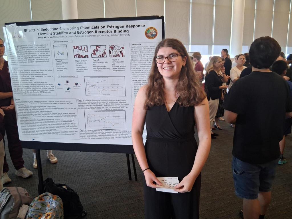 Emily Kirchner in front of research poster presentation.