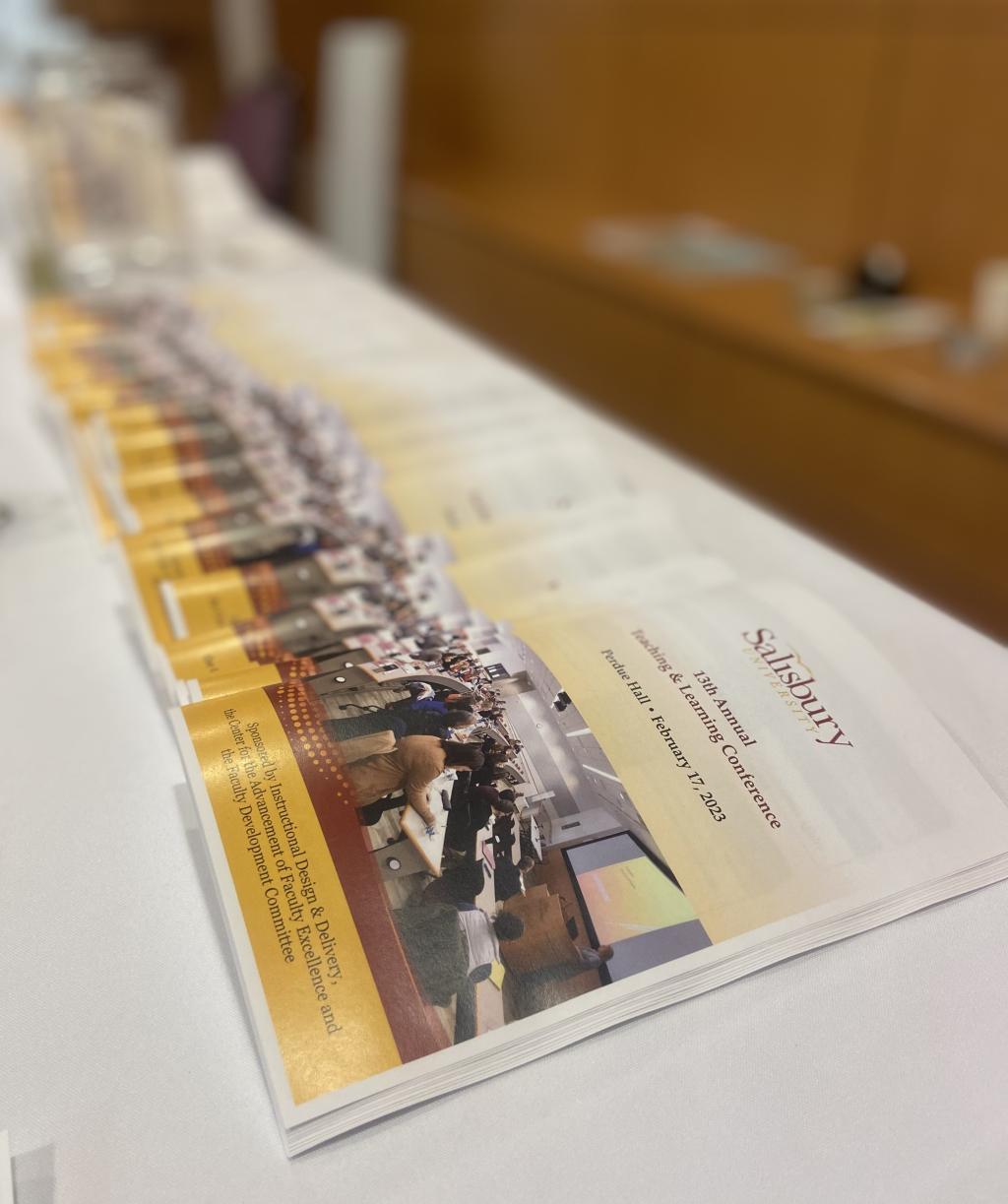 Teaching & Learning Conference programs arranged on the check-in table.