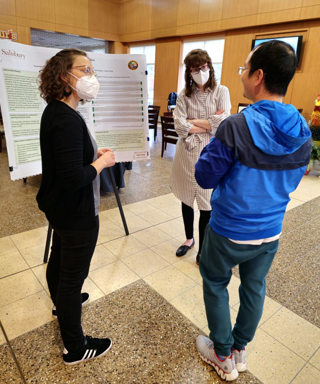 Three Teaching & Learning Conference participants discuss a poster presentation during the lunchtime poster session. 