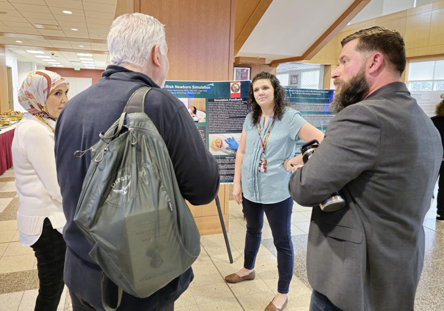 Four Teaching & Learning Conference participants discuss a poster presentation during the lunchtime poster session. 