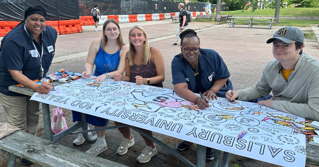 Employees and Students Coloring a Centennial Banner