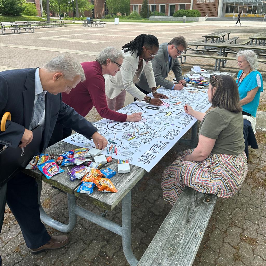 Employees and Students Coloring a Centennial Banner